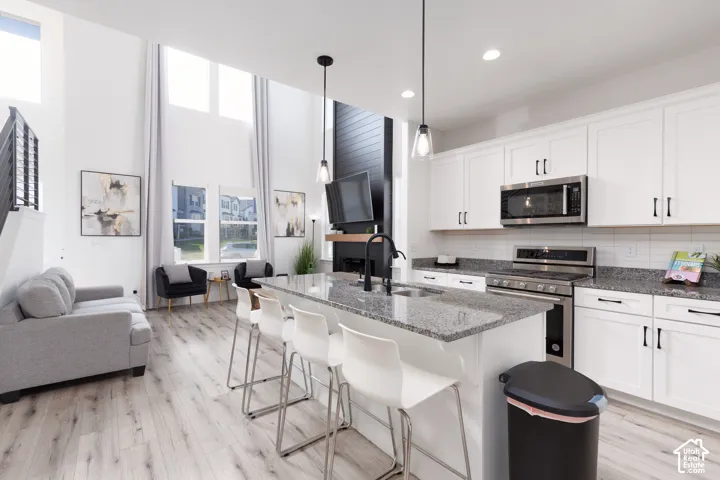 Open-concept kitchen featuring an island with seating, stainless steel appliances, and white cabinetry