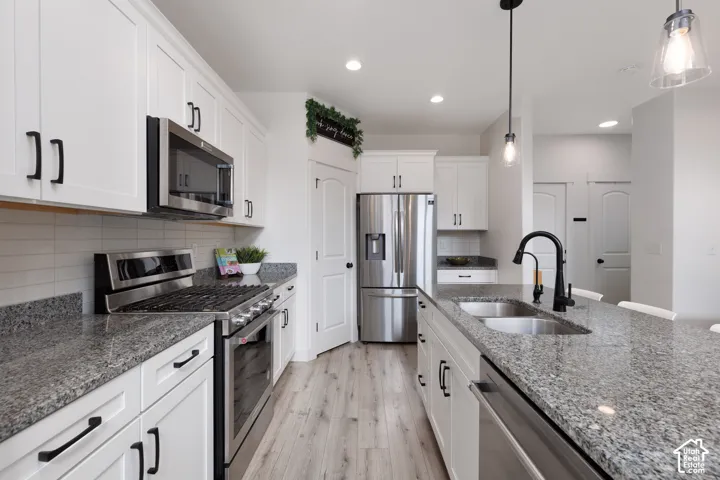 Kitchen featuring white shaker cabinetry, stainless steel appliances, granite countertops, wood-finish flooring, and recessed lighting