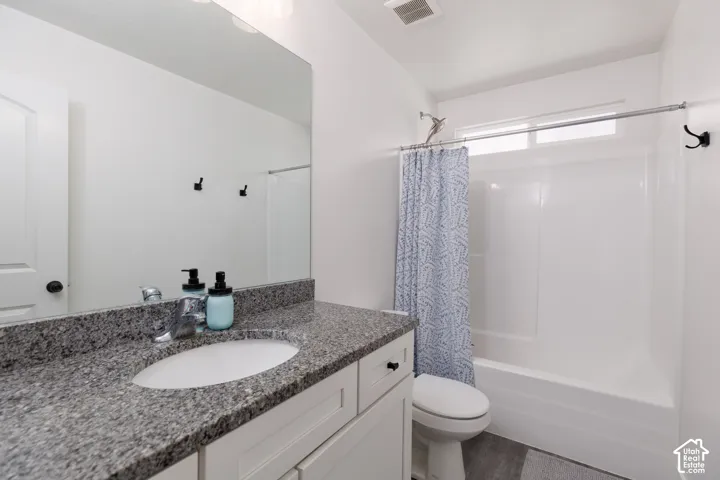 White vanity with shaker-style cabinetry, granite countertop, oval undermount sink, and a large wall-mounted mirror