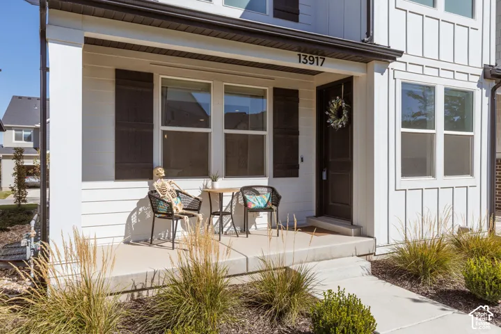 White siding exterior with dark shutters, board-and-batten accent, dark entry door, and concrete porch