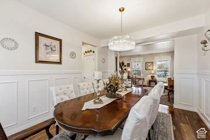 Dining area featuring wainscoting, wood-finish flooring, and a crystal chandelier