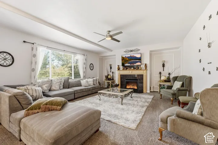 Living space featuring a fireplace with a stone surround and mantel, a ceiling fan, and large windows
