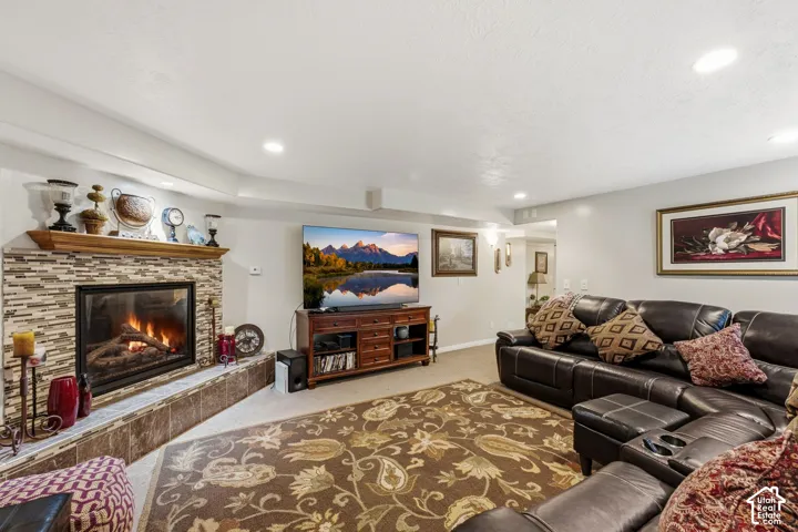 Recessed lighting throughout, corner fireplace with tile surround, wood mantel, and hearth, and light wall finishes