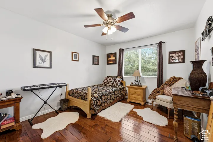 Wood-finish flooring, ceiling fan with integrated lighting, and a large window with blinds
