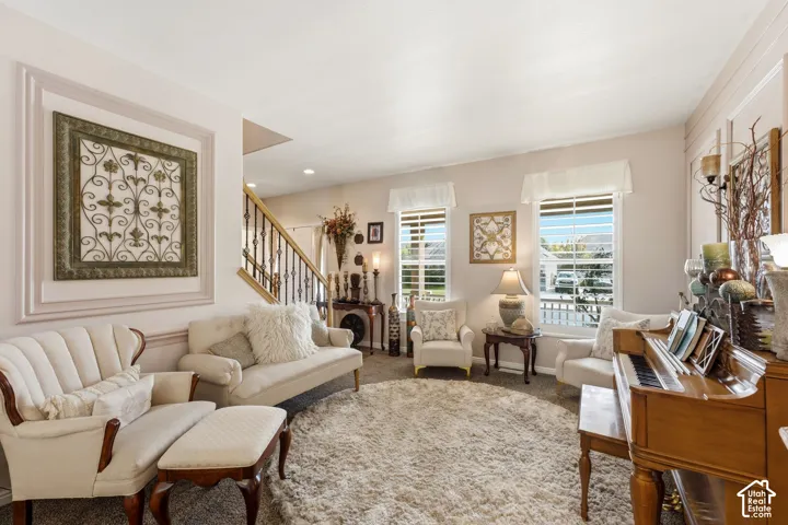 Architectural wall trim, multiple windows with blinds, a staircase featuring a wrought iron railing, and recessed lighting