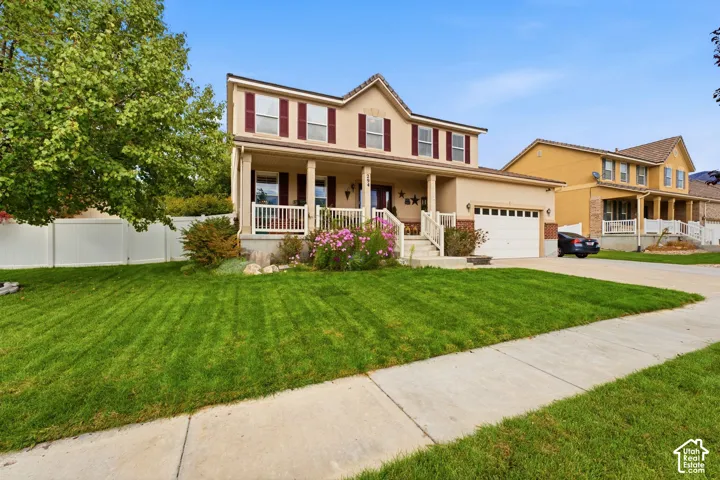 Two-story residence featuring a covered front porch, attached garage, and a concrete driveway
