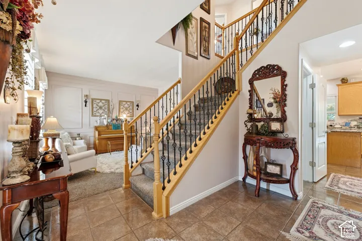 Staircase with wood banister and wrought iron spindles, tile flooring, and wall paneling