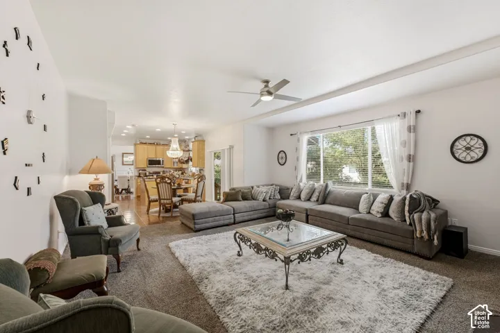 Expansive living area with neutral carpeting, a large window, and a ceiling fan
