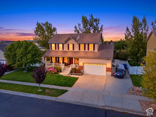 Two-story home featuring a covered front porch with railings, an attached two-car garage, and a concrete driveway