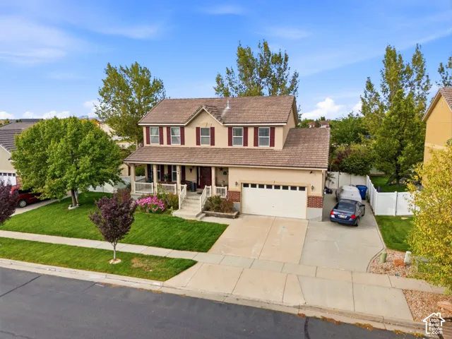 Two-story residence with a covered front porch, attached garage, and a concrete driveway