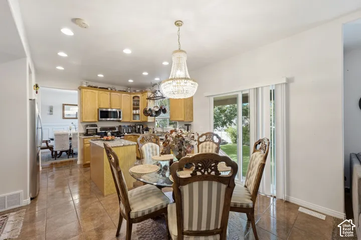 Recessed lighting, tile flooring, glass sliding doors, stainless steel appliances, and a kitchen island with stone countertops