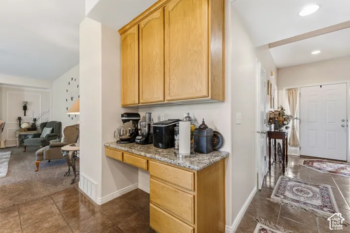 Built-in cabinetry with a granite-style countertop and tile flooring