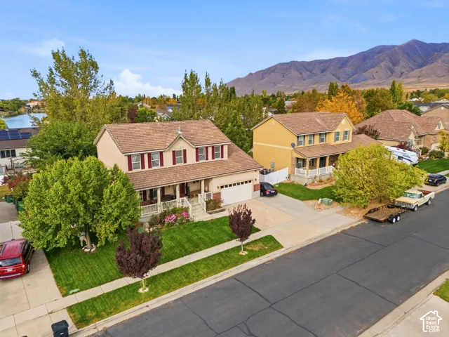 Two-story residence featuring a covered front porch, attached garage, and a lush lawn