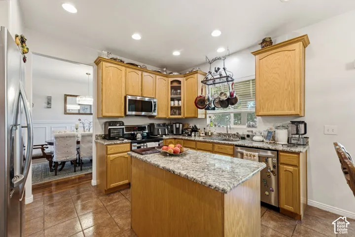 Kitchen featuring wood cabinetry, stainless steel appliances, a center island with a stone countertop, and recessed lighting