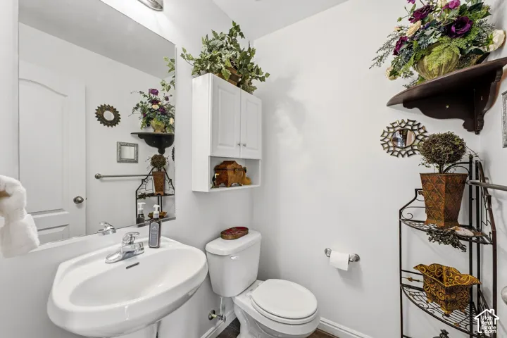 Pedestal sink with chrome faucet, full-width mirror, wall-mounted storage cabinet, and white toilet