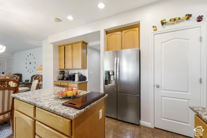 Kitchen featuring wood cabinetry, stainless steel refrigerator, white paneled door, and granite countertops