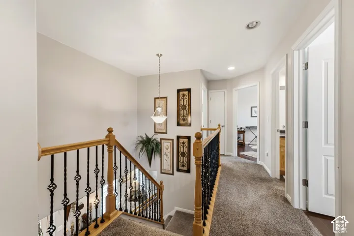 Carpeted hallway with multiple doorways, recessed lighting, and a hanging pendant light