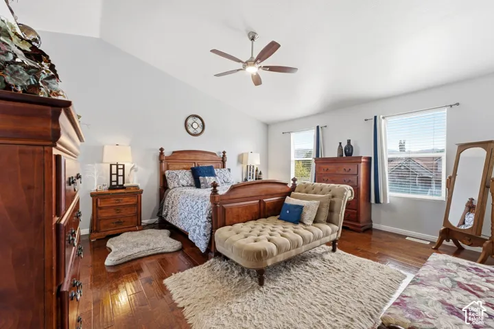 Vaulted ceiling, ceiling fan with integrated lighting, wood-finish flooring, and multiple windows