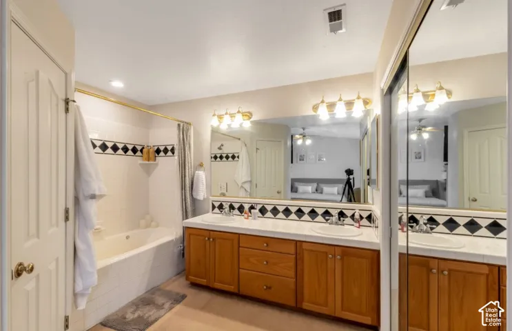 Double vanity with undermount sinks, wood-finish cabinetry, and expansive mirrors