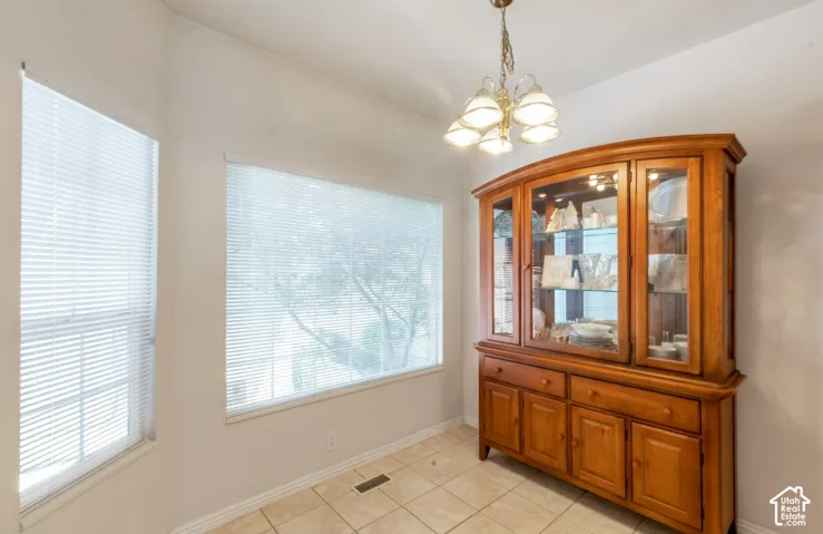 Tile flooring with a decorative light fixture, complemented by multiple windows providing natural illumination