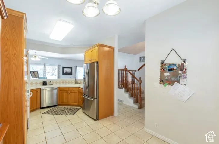 Kitchen featuring wood-finish cabinetry, stainless steel appliances, tiled flooring, and a tiled backsplash