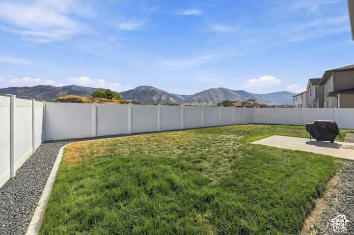Expansive backyard featuring a manicured lawn, a white privacy fence, and a concrete patio