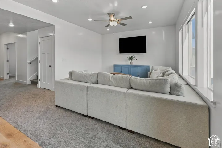 Plush gray carpeting, recessed lighting, and a ceiling fan with integrated light fixture