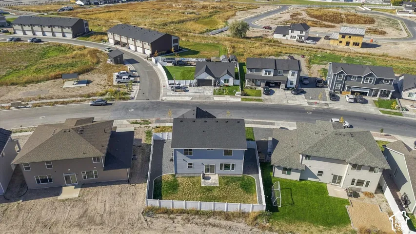 Residential property featuring a paved street, established homes with dark roofs, manicured lawns, and a partially developed neighborhood setting