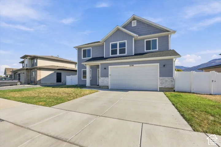 Two-story residence featuring light blue siding with white trim, a two-car garage, and a concrete driveway