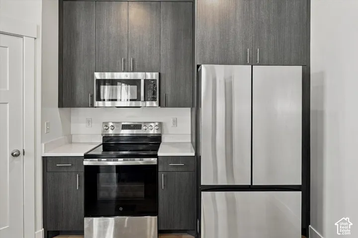 Full appliance package featuring a stainless steel refrigerator, microwave, and range