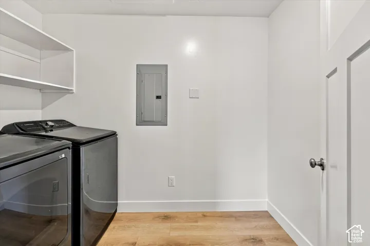 Laundry area featuring wood-finish flooring, white walls, and built-in white shelving