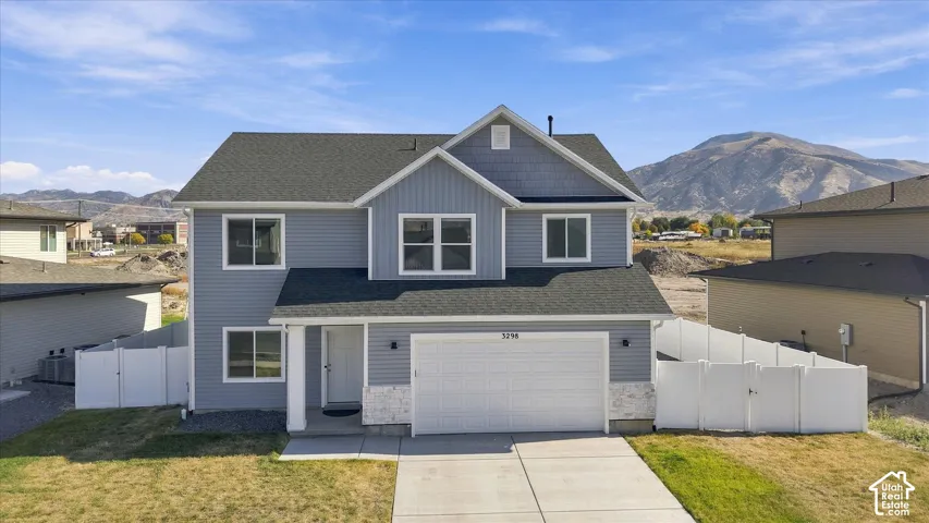Two-story residence featuring light blue siding, a two-car garage, white trim, and a partial stone facade