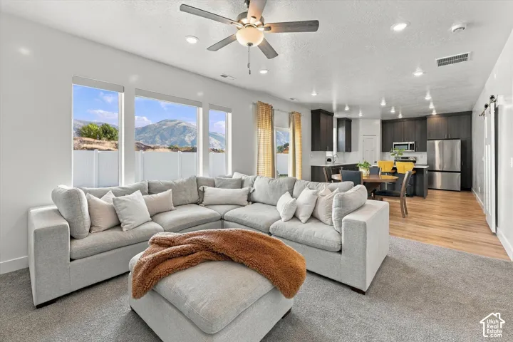 Open-concept living area with integrated kitchen, recessed lighting, ceiling fan, and hardwood-finish flooring in kitchen
