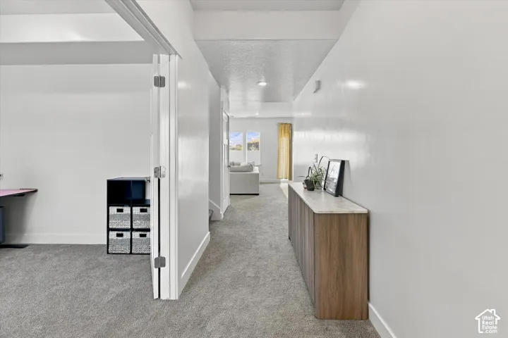 Recessed lighting, wood-finish console with stone top, light gray carpeting, white walls, and white trim