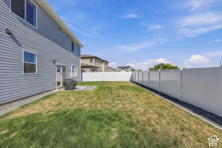 Spacious grassy yard featuring a white privacy fence and a concrete patio pad
