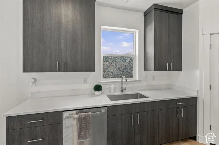 Dark wood-finish cabinetry, light-toned countertops, stainless steel sink, and a built-in stainless steel dishwasher