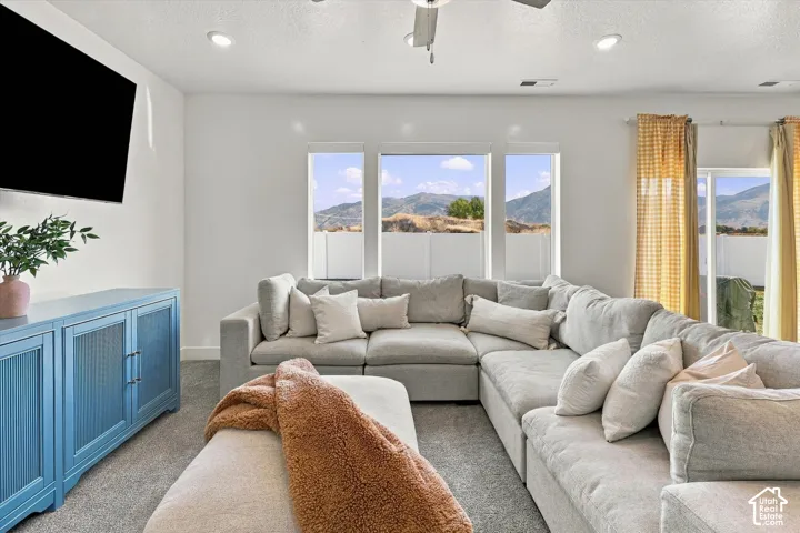 Recessed lighting, ceiling fan, multiple windows, and light-colored carpeting