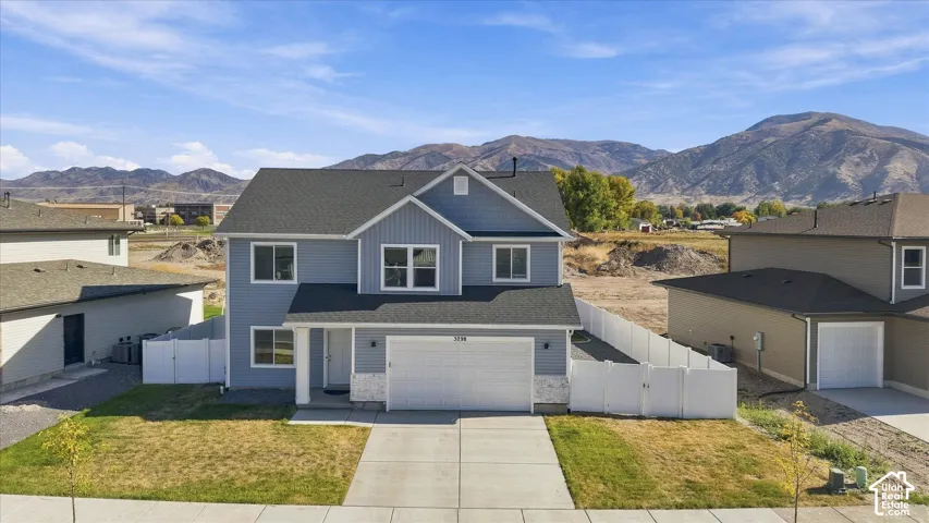 Two-story residence featuring light blue siding, a two-car garage, and white perimeter fencing