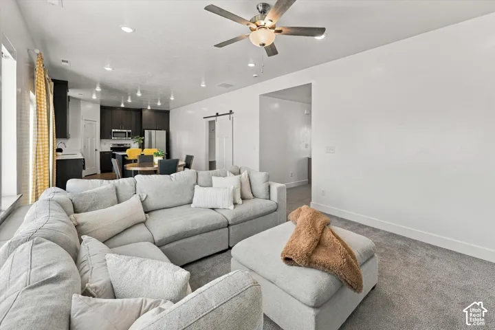 Open-concept living area with recessed lighting, dark wood-finish cabinetry, stainless steel appliances, and a barn door entry