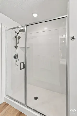 Sliding glass shower enclosure with chrome hardware, an adjustable showerhead, and a built-in shelving niche
