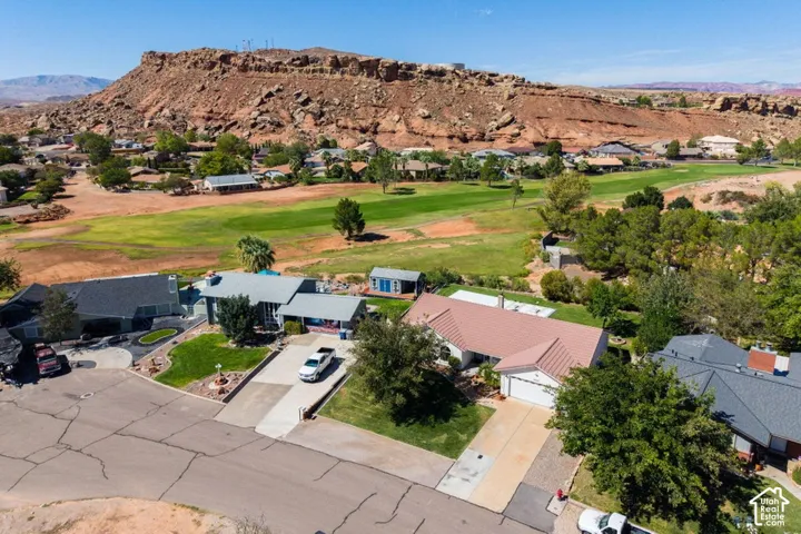 Residential property featuring a red rock mountain backdrop, golf course access, and a paved street