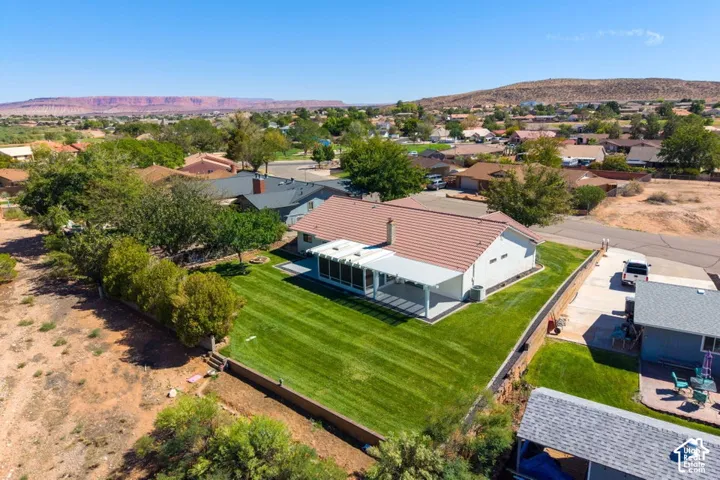 Expansive green lawn with a covered patio, solid perimeter fencing, and mature landscaping