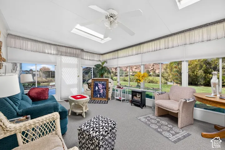 Sunroom featuring extensive window-lines, skylights, a ceiling fan, and carpeted flooring