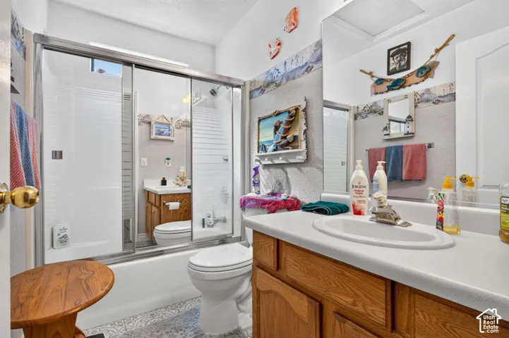 Bathroom featuring a vanity with an integrated sink, wood-finish cabinetry, a framed mirror, and a shower-tub combination with sliding glass doors