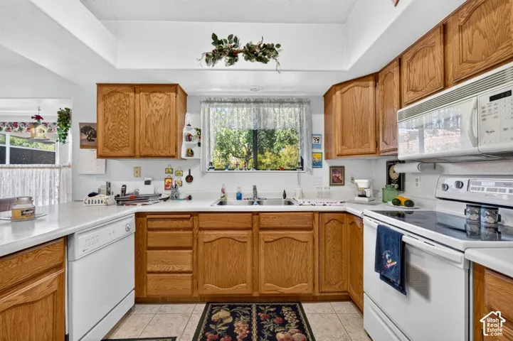 U-shaped kitchen featuring light wood cabinetry, white countertops, a built-in microwave, and a white electric range