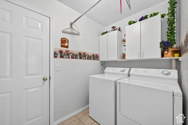 Laundry area featuring tile flooring, white shaker cabinetry, an upper storage shelf, and a white paneled door