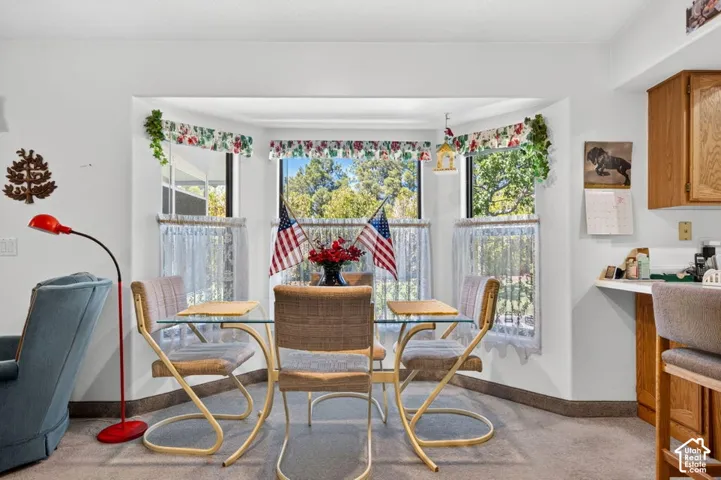 Bay window with abundant natural light, carpeted flooring, white walls, and wood-finish cabinetry