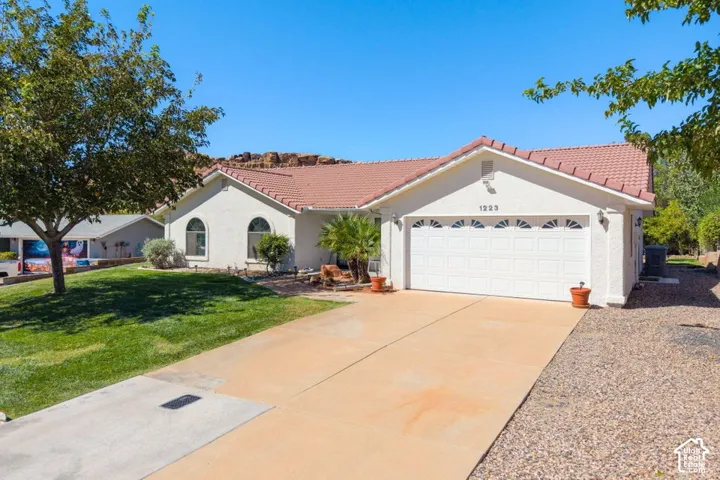 Stucco exterior with a tiled roof, arched windows, an attached two-car garage, and a concrete driveway