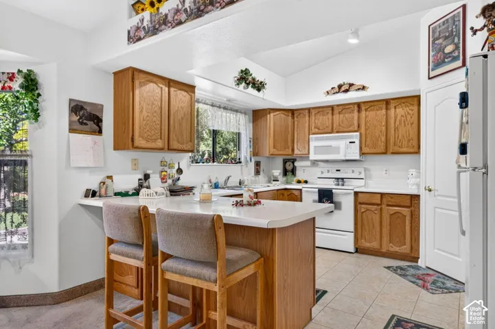 Kitchen featuring wood cabinetry, white countertops, a white appliance package, and tile flooring