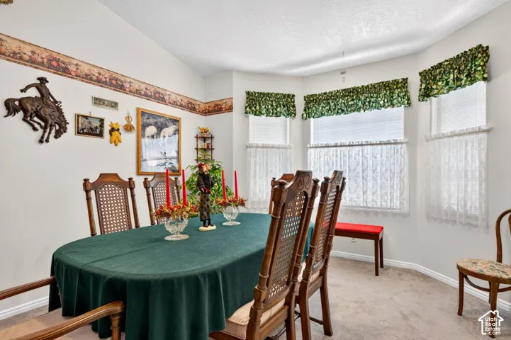 Bay window with multiple panes, vaulted ceiling, and neutral carpet flooring